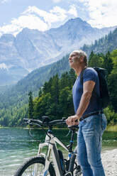 Senior man with e-bike at Eibsee lakeside - DIGF12135