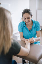 Physiotherapeutin bei der Handmassage eines Patienten - DAWF01535