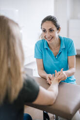 Physiotherapeutin bei der Handmassage eines Patienten - DAWF01536