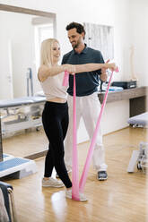 Physiotherapeutin hilft einer Patientin, die mit einem Fitnessband übt - DAWF01568