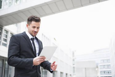 Young businessman using digital tablet outside office building - DIGF12191