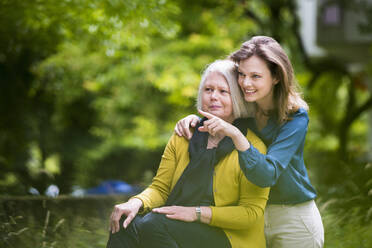 Portrait of senior woman and adult daughter watching something in a park - DIGF12197