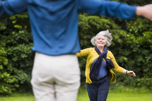 Porträt einer glücklichen älteren Frau, die zu ihrer erwachsenen Tochter in einem Park läuft - DIGF12208