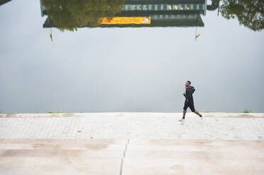 Young man jogging at riverside - DIGF12231