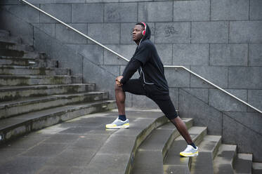 Young jogger stretching his leg in the city - DIGF12236