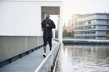 Young man with headphones jogging in the city - DIGF12239