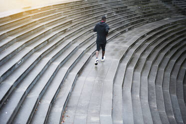 Rückansicht eines jungen Mannes beim Joggen auf einer Treppe - DIGF12240