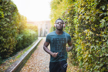 Young man with headphones jogging in park - DIGF12241