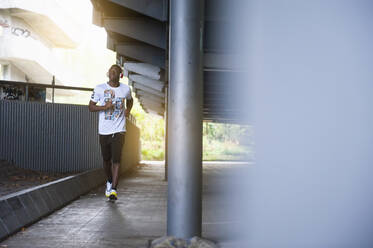 Junger Mann beim Joggen in der Stadt - DIGF12245