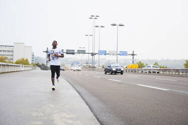 Junger Mann joggt auf der Straße in der Stadt - DIGF12251