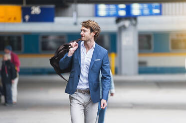 Portrait of young businessman with bag at train station - DIGF12298