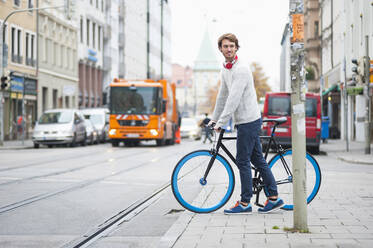 Porträt eines jungen Mannes mit Fahrrad in der Stadt - DIGF12304