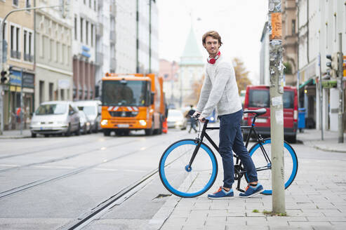 Porträt eines jungen Mannes mit Fahrrad in der Stadt - DIGF12304