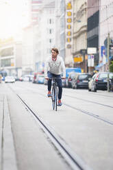 Junger Mann fährt Fahrrad in der Stadt - DIGF12305