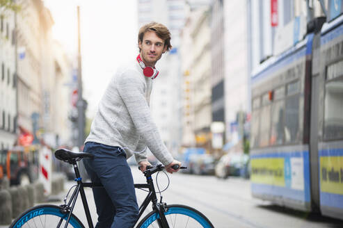 Porträt eines jungen Mannes mit Fahrrad in der Stadt - DIGF12306