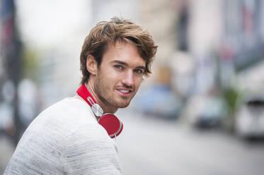 Portrait of young man with red headphones - DIGF12307