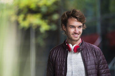 Portrait of smiling young man with headphones - DIGF12309