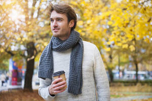 Porträt eines jungen Mannes mit Kaffee zum Mitnehmen im Herbst - DIGF12311