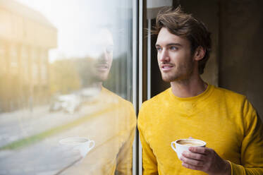Portrait of young man in a coffee shop looking out of window - DIGF12316