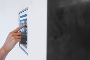 Hand of woman using digital lightning control mounted on wall at home - DIGF12326