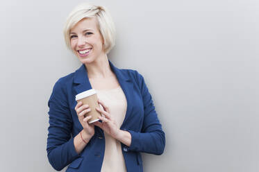 Porträt einer blonden Geschäftsfrau mit Kaffee zum Mitnehmen - DIGF12360