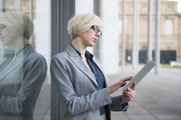 Portrait of blond businesswoman using tablet in the city - DIGF12365