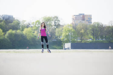 Junge Frau auf Inline-Skates in einem Park an einem sonnigen Tag - DIGF12390