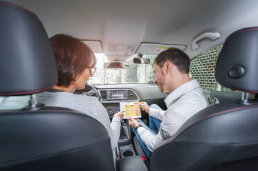 Female learner driver with instructor in car looking at test script - DIGF12405