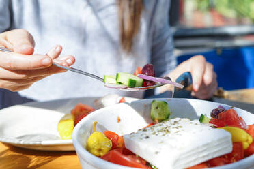 Ein Löffel mit mediterranem Salat, gehalten von einer Frau - CAVF83021