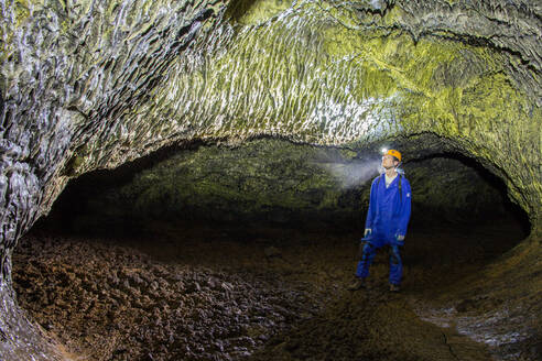 Ein Wissenschaftler bewundert gelbe Mikroben an der Decke einer Lavaröhrenhöhle - CAVF83029