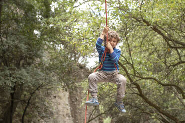 Four year old smily toddler plays hanging from a climbing rope - CAVF83047