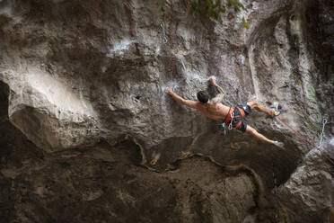 One tattooed man with no shirt stretches while rock climbing in Mexico - CAVF83051