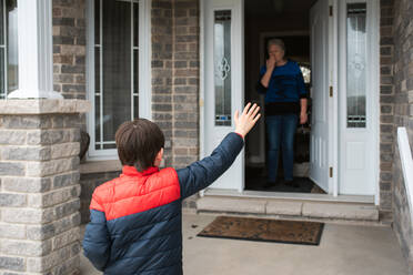 Social distance visit between young boy and his grandmother at home. - CAVF83073