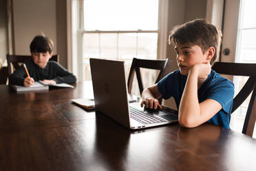 Boys working on their homework on a laptop commuter at home. - CAVF83081