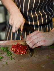 Close up of chef chopping red chili peppers at commercial kitchen - CAVF83189