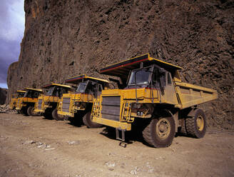 Yellow dump trucks parked at side of a cliff - CAVF83203