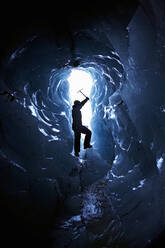 Silhouette of mature man at the entrance of a small Ice cave - CAVF83210