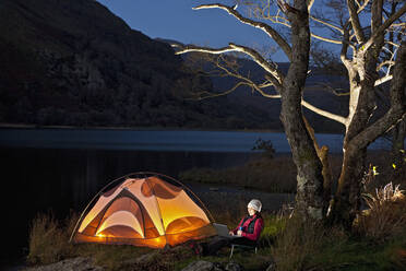 Wanderin schaut auf ihren Laptop im Camp in Nordwales - CAVF83220