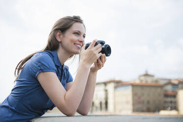 Porträt einer glücklichen Frau, die mit einer Digitalkamera Fotos macht, Florenz, Italien - DIGF12446