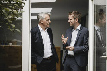 Two businessmen standing in office door, talking - GUSF03810