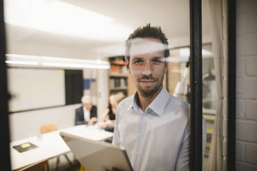 Geschäftsmann mit digitalem Tablet, Blick aus dem Bürofenster - GUSF03834