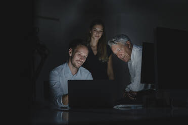 Ein Team von Geschäftsleuten arbeitet bis spät in die Nacht im Büro, um Lösungen zu diskutieren - GUSF03863