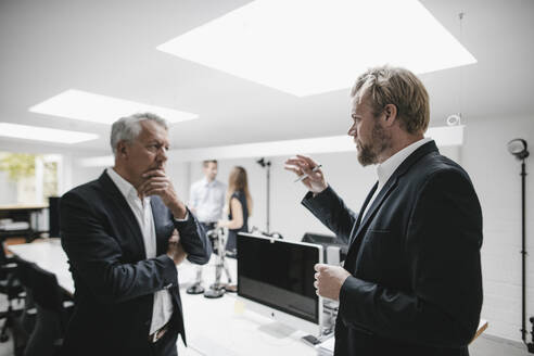 Zwei Geschäftsleute diskutieren bei einem Treffen im Büro - GUSF03882