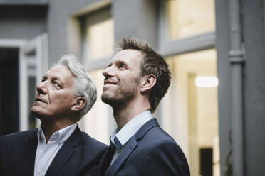 Two successful businessmen, looking at up, smiling - GUSF03909