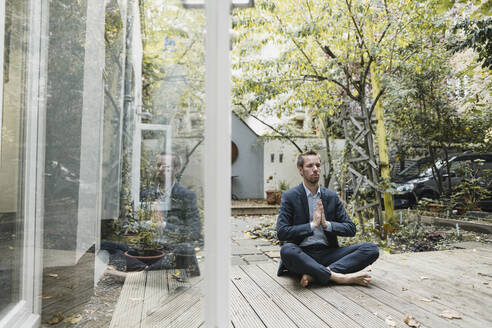 Businessman practicing yoga in backyard - GUSF03926