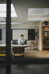 Geschäftsmann, der in einem Loft-Büro sitzt und ein digitales Tablet benutzt - GUSF03934