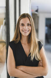 Young businesswoman standing in office, with arms crossed - GUSF03948