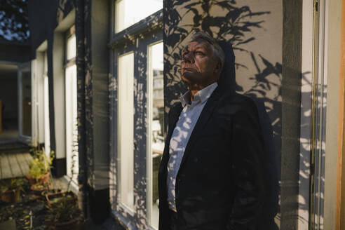 Senior businessman working overtime, taking a break in the backyard of his office - GUSF03973