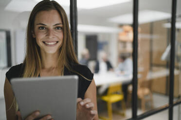 Junge Geschäftsfrau im Büro stehend, mit digitalem Tablet - GUSF04008