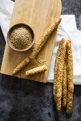 Schneidebrett und frische italienische Grissini-Brotstangen mit Sesam - GIOF08223